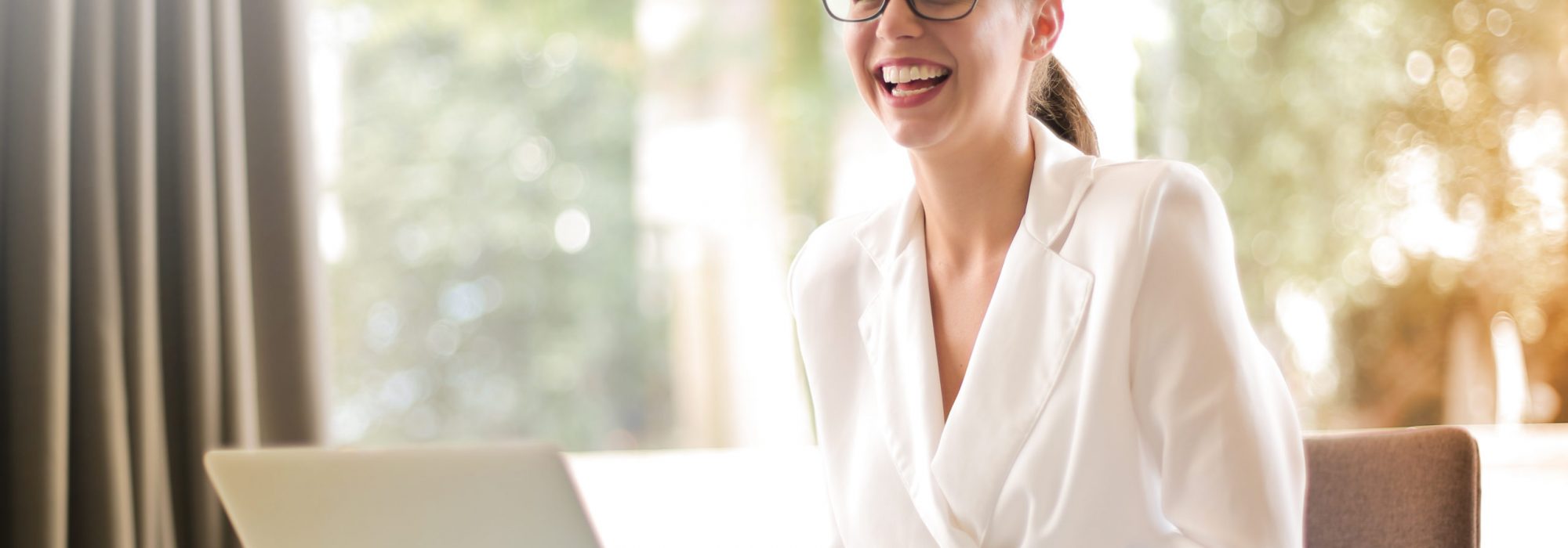 laughing-businesswoman-working-in-office-with-laptop-3756679
